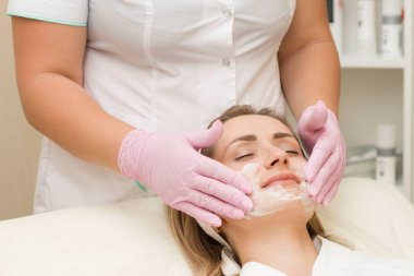 Kozmetik uzmanının randevusundaki genç bir kadın yüzüne krem sürmüş. Güzellik tedavisi