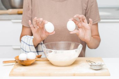 Genç bir kadın para kazanıyor. Masanın üzerinde: un, yumurta, tuz.