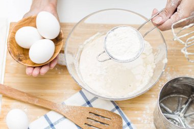 Genç bir kadın para kazanıyor. Masanın üzerinde: un, yumurta, tuz, paskalya pastası.