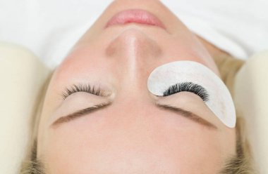 Kirpik uzatma prosedürü. Uzun kirpikli bir kadın gözü. Kırbaçlar, yakın çekim, makro, seçici odaklanma.