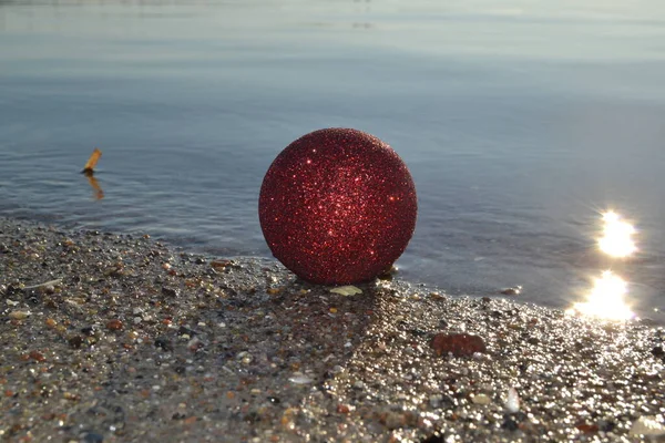 Rosso Ornamento Natalizio Sdraiato Sulla Sabbia Riva Mare — Foto Stock