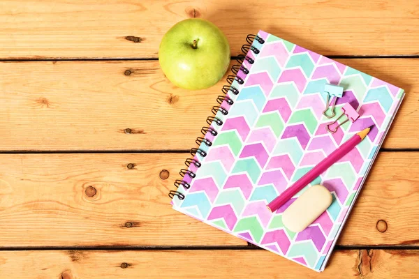 Cuaderno rosa y manzana sobre fondo de madera — Foto de Stock