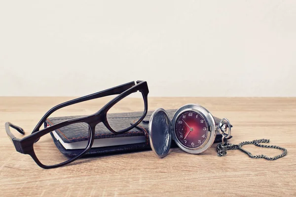 Reloj de bolsillo, gafas y un planificador en una mesa — Foto de Stock