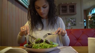 Bir tabağa yakın kadın kapalı bir kafede yemek salata.