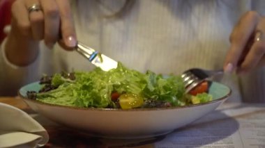 Bir tabağa yakın kadın kapalı bir kafede yemek salata.