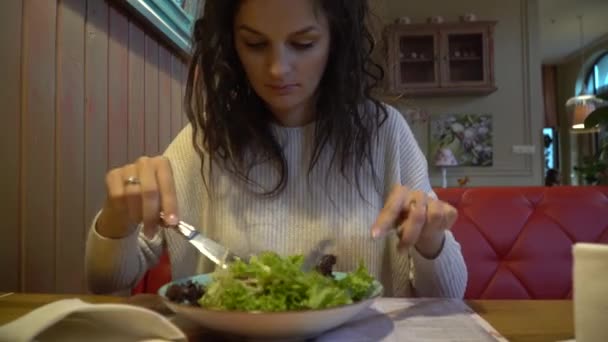 Mujer comiendo ensalada en un café de interior, de cerca en un plato . — Vídeos de Stock