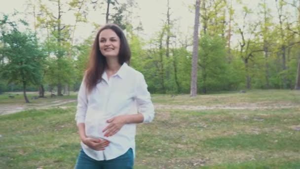 Mulher grávida segurando sua barriga andando sob tentativas de verão — Vídeo de Stock