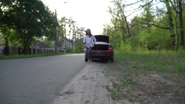 Mulher está colocando um triângulo de aviso e chamando assistência na estrada . — Vídeo de Stock