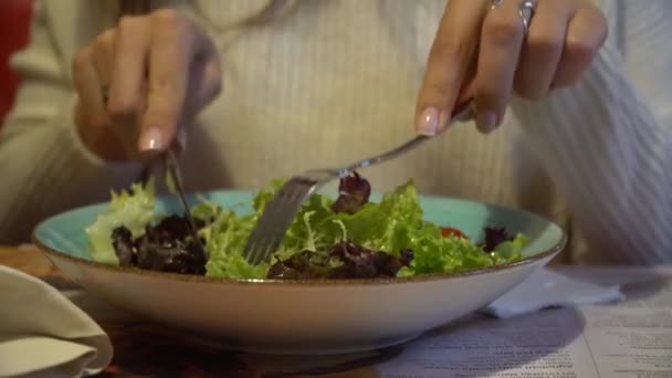 Vrouw eten salade in een overdekt café, close-up op de plaat. — Stockvideo