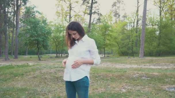 Femme enceinte tenant son ventre marchant sous les essais d'été — Video