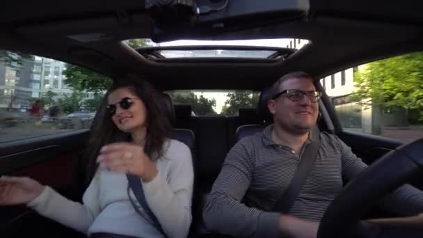Paar lachen en knuffelen in de auto rijden — Stockvideo