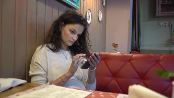 Mujer usando la aplicación en el teléfono inteligente en la cafetería — Vídeos de Stock