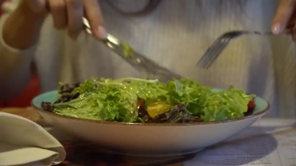 Mujer comiendo ensalada en un café de interior, de cerca en un plato . — Vídeo de stock