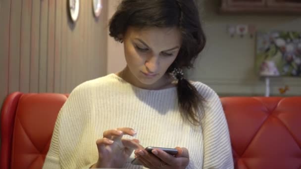 Mujer usando la aplicación en el teléfono inteligente en la cafetería — Vídeo de stock