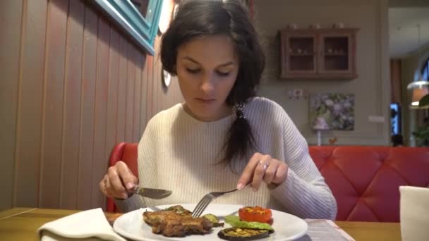 Vrouw genieten van de smaak van gegrilde steak in restaurant — Stockvideo