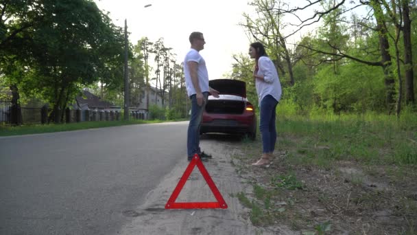 Ehepaar streitet vor kaputtem Auto auf ruhiger Landstraße. — Stockvideo