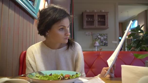 Vrouw naar op zoek is via het menu in restaurant — Stockvideo