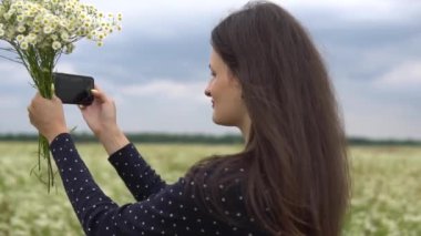 Güzel kız selfie, papatya çiçekleri dışında fotoğraf yapıyor.