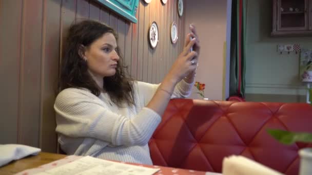 Schöne aufregende junge Frau macht Selfieein Café. — Stockvideo