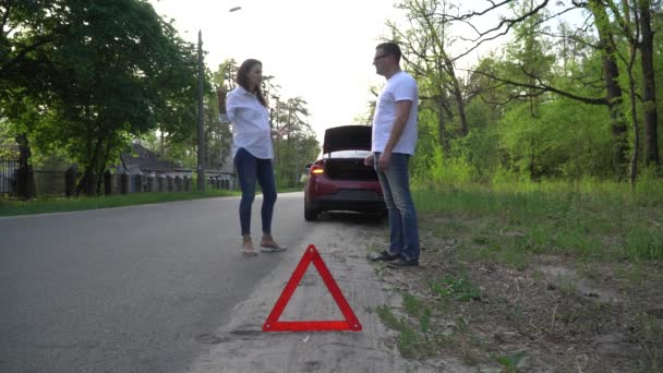 Ehepaar streitet vor kaputtem Auto auf ruhiger Landstraße. — Stockvideo