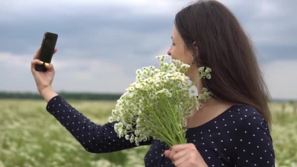 Krásná holka dělá selfie, Foto s květy heřmánku mimo. — Stock video
