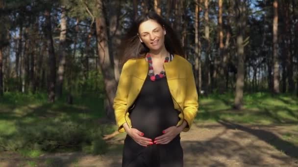 Женщина трогает ее беременный живот — стоковое видео
