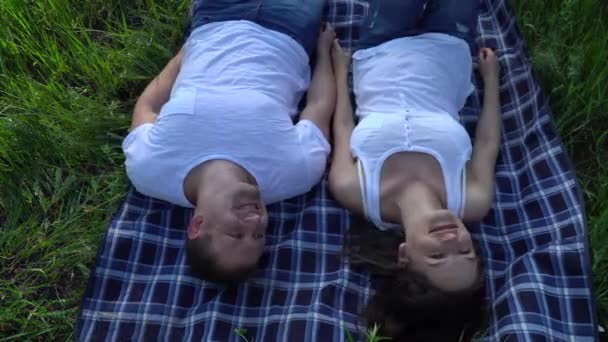 Щаслива усміхнена пара лежить на траві і розслабляється — стокове відео