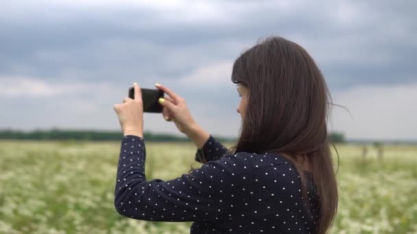 Mooi meisje doet selfie, foto met kamille bloemen buiten. — Stockvideo