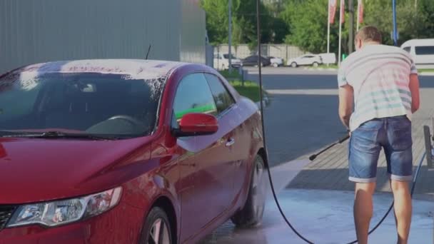 Kaukasische jongeman wassen van zijn auto op de Autowassen selfservice. Auto wassen. — Stockvideo