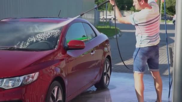 Un joven caucásico lavando su coche en el auto-servicio de lavado. Lavado de coches . — Vídeos de Stock