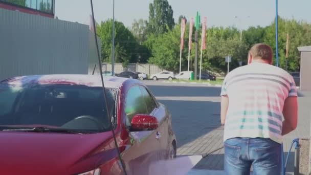 Un joven caucásico lavando su coche en el auto-servicio de lavado. Lavado de coches . — Vídeos de Stock