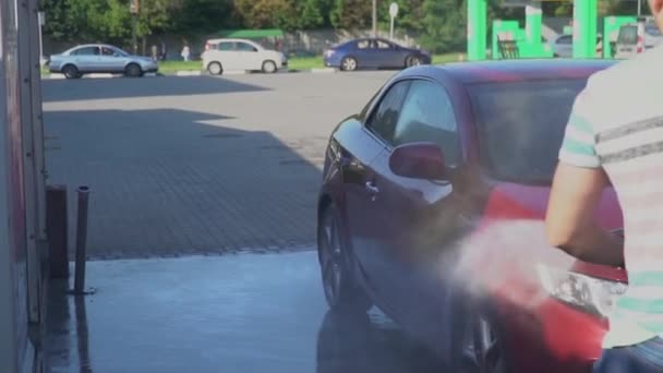 Ung kaukasiska man tvätta bilen på biltvätt självbetjäning. Biltvätt. — Stockvideo