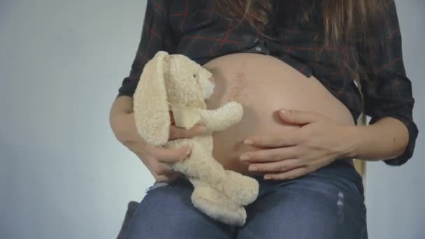 Беременная женщина играет с плюшевой игрушкой кролика позирует — стоковое видео