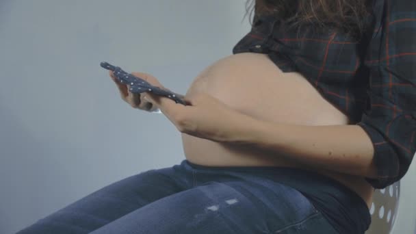 Těhotná žena se dívá na oblečení její budoucí dítě — Stock video