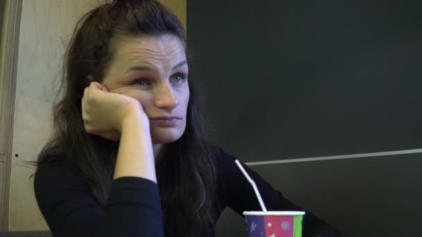 Chica aburrida sentada junto a la mesa en la cafetería . — Vídeos de Stock