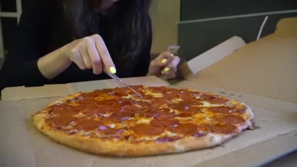 Mulher é uma fatia de pizza em um restaurante. Uma mulher corta uma pizza . — Vídeo de Stock