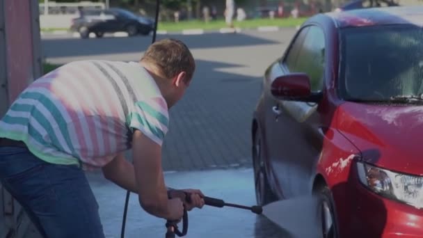 Jeune homme caucasien laver sa voiture sur le libre-service de lavage de voiture. Lavage de voiture . — Video