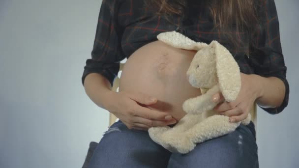 Беременная женщина играет с плюшевой игрушкой кролика позирует — стоковое видео