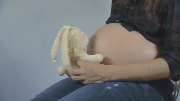 Gravid kvinna leker med en bunny plysch leksak poserar — Stockvideo