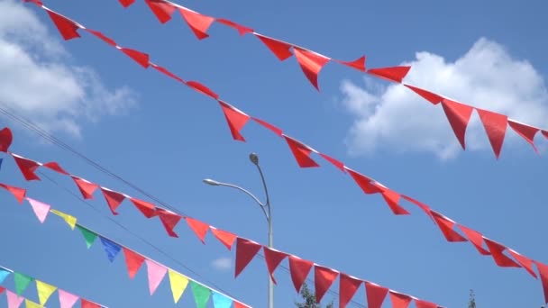 Barevné řetězce praporkem trojúhelník vlajky vlající ve větru. — Stock video