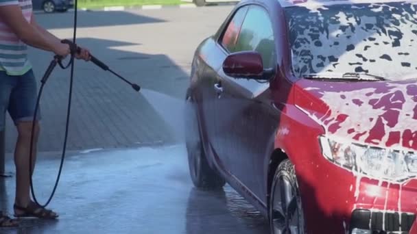 Un joven caucásico lavando su coche en el auto-servicio de lavado. Lavado de coches . — Vídeos de Stock