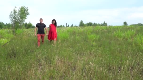 Bonito casal homem e mulher grávida com cabelos longos em um vestido vermelho. família . — Vídeo de Stock