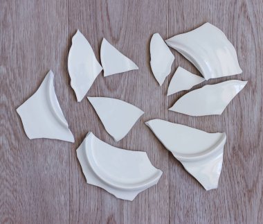 Yerde kırık beyaz bir tabağın parçaları var. Yatay oryantasyon. Seçici odak.