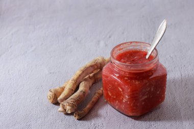 Şeffaf bir kavanozda domatesli, sarımsaklı ve yabanturplu baharatlı aperatif. Yabanturpunun kökleri. Kış için hasat. Soğuk önleme. Mesaj için yer. Yakın plan..