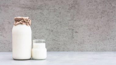 Gri arka planda, şişedeki taze süt. Kefir, süt veya Türk Ayran cam bir şişede içer. Dünya süt günü konsepti. Metin için boşluk.
