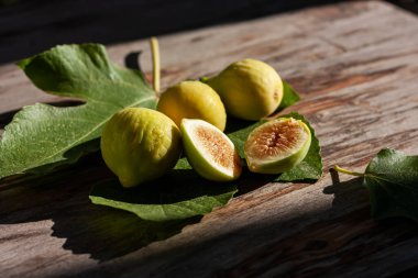 Tahta masa üzerinde yaprak ile olgunlaşmış sarı incir meyvesi. Hasat ve sağlıklı beslenme konsepti. Seçici odak.