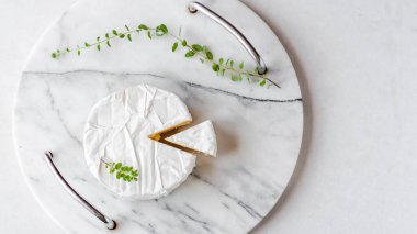 Yuvarlak Brie peyniri, beyaz arka planda mermer tepside kesilmiş bir bölüm. Taze Camembert peyniri. Fransız peyniri manzaralı. Boşluğu kopyala.