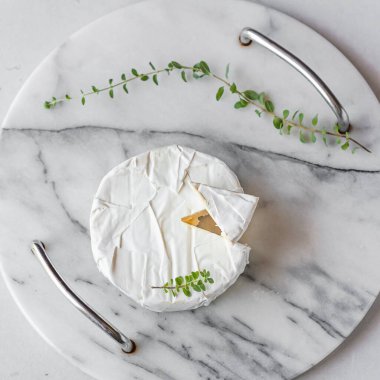 Yuvarlak Brie peyniri, beyaz arka planda mermer tepside kesilmiş bir bölüm. Taze Camembert peyniri. Fransız peyniri üst görünümü.