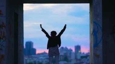 Terk edilmiş binada hayattan zevk alacakaranlık, eller yukarı kaldırdı, şehir genç