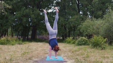 Kadın acrobat el stand açık havada gerçekleştirir, denge egzersiz güçlü eller yavaş